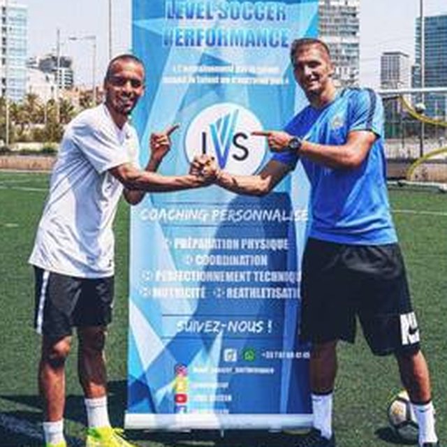 Coach Salim et un joueur se saluant devant la bâche Level Soccer Performance