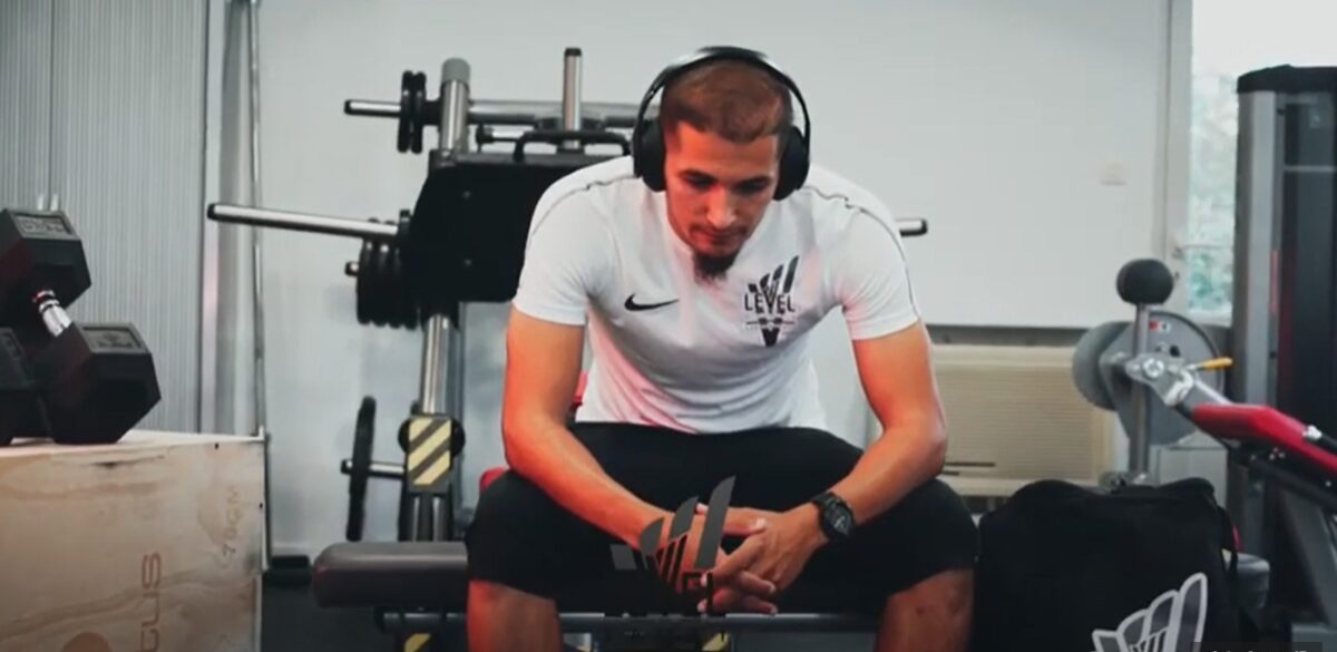 Coach Salim assis sur un banc de musculation, casque sur les oreilles, avant une séance