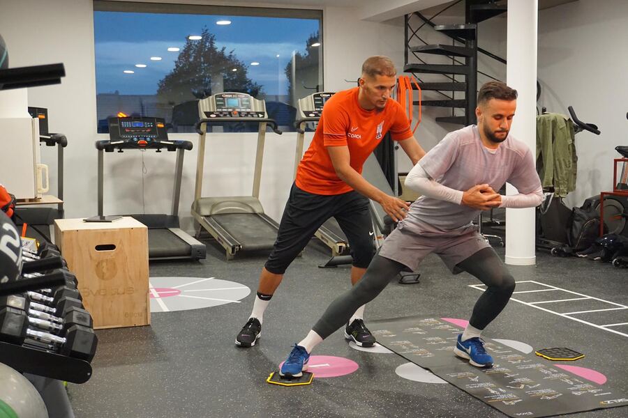 Coach Salim guide un athlète pendant un exercice en salle